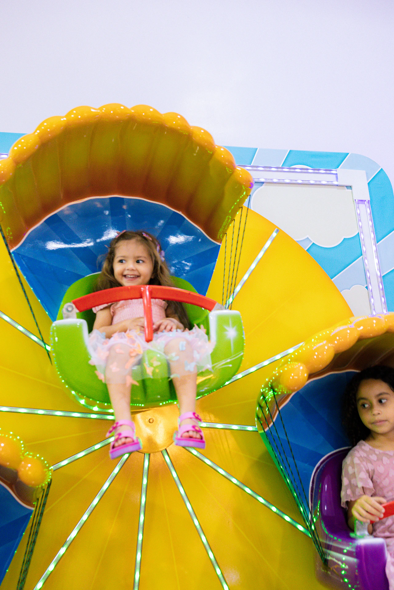 Menina sorrindo no brinquedo colorido durante festa de aniversário infantil