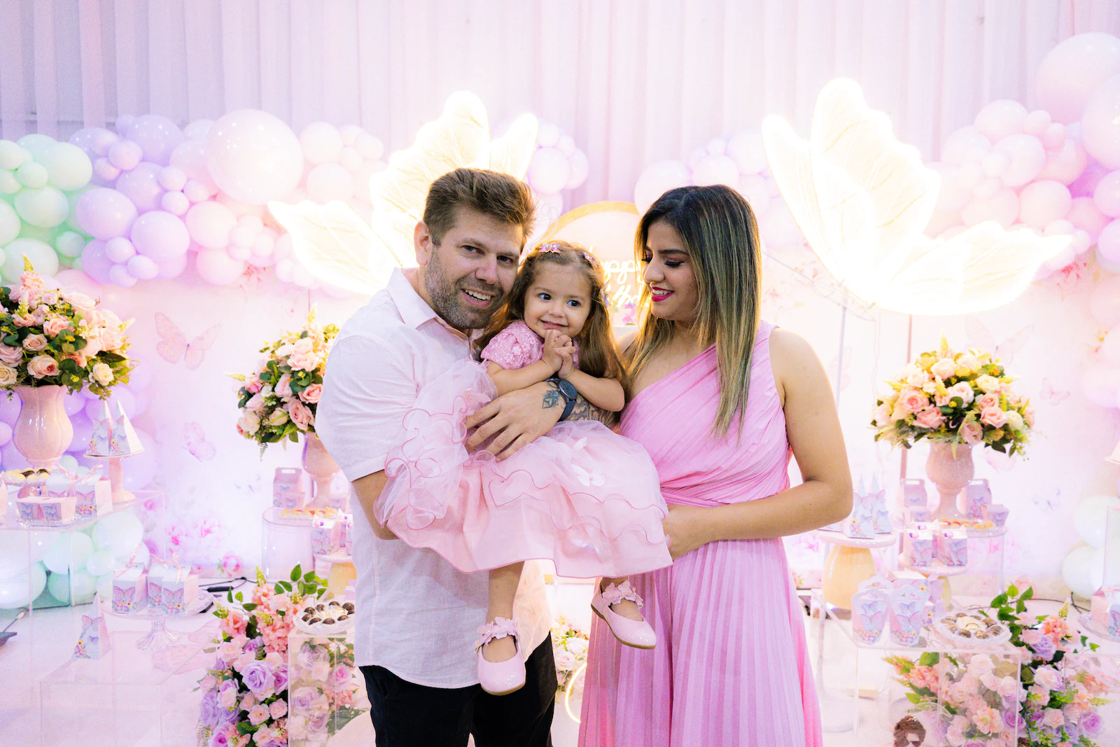 Retrato da família com a aniversariante diante da decoração da festa infantil