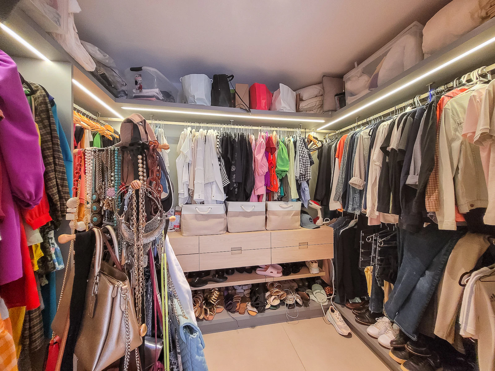 Closet da suíte master com araras de roupas e gavetas iluminadas