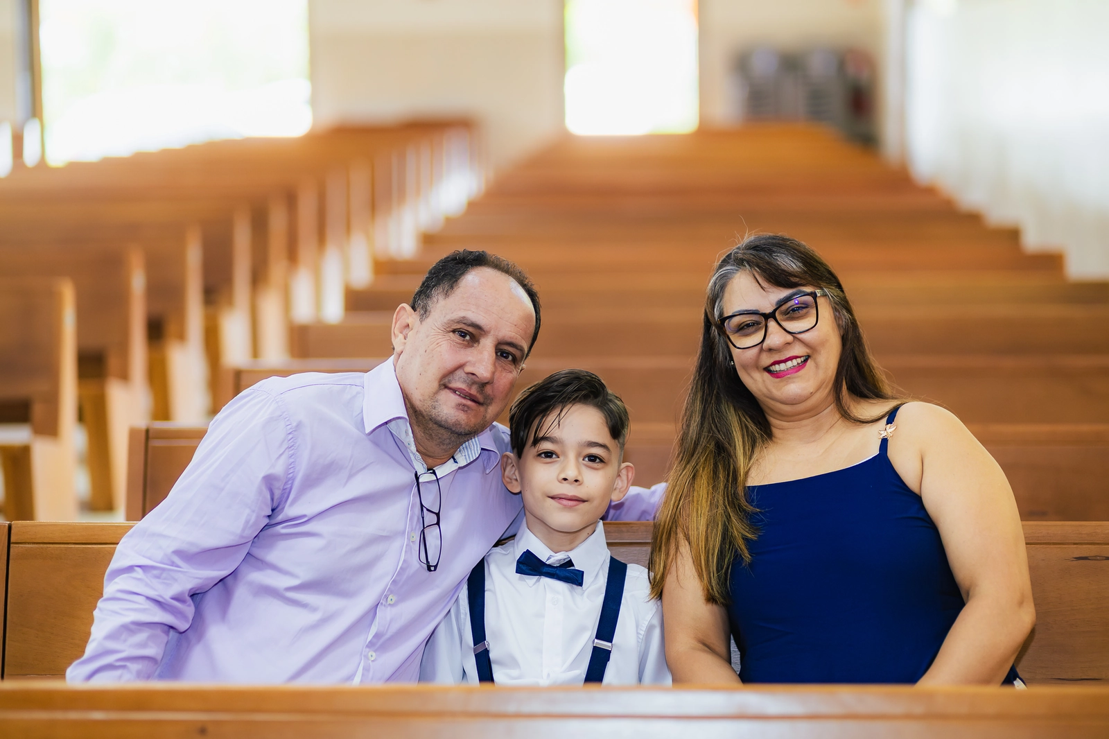 Pais e o filho mais velho posando na igreja durante o batizado