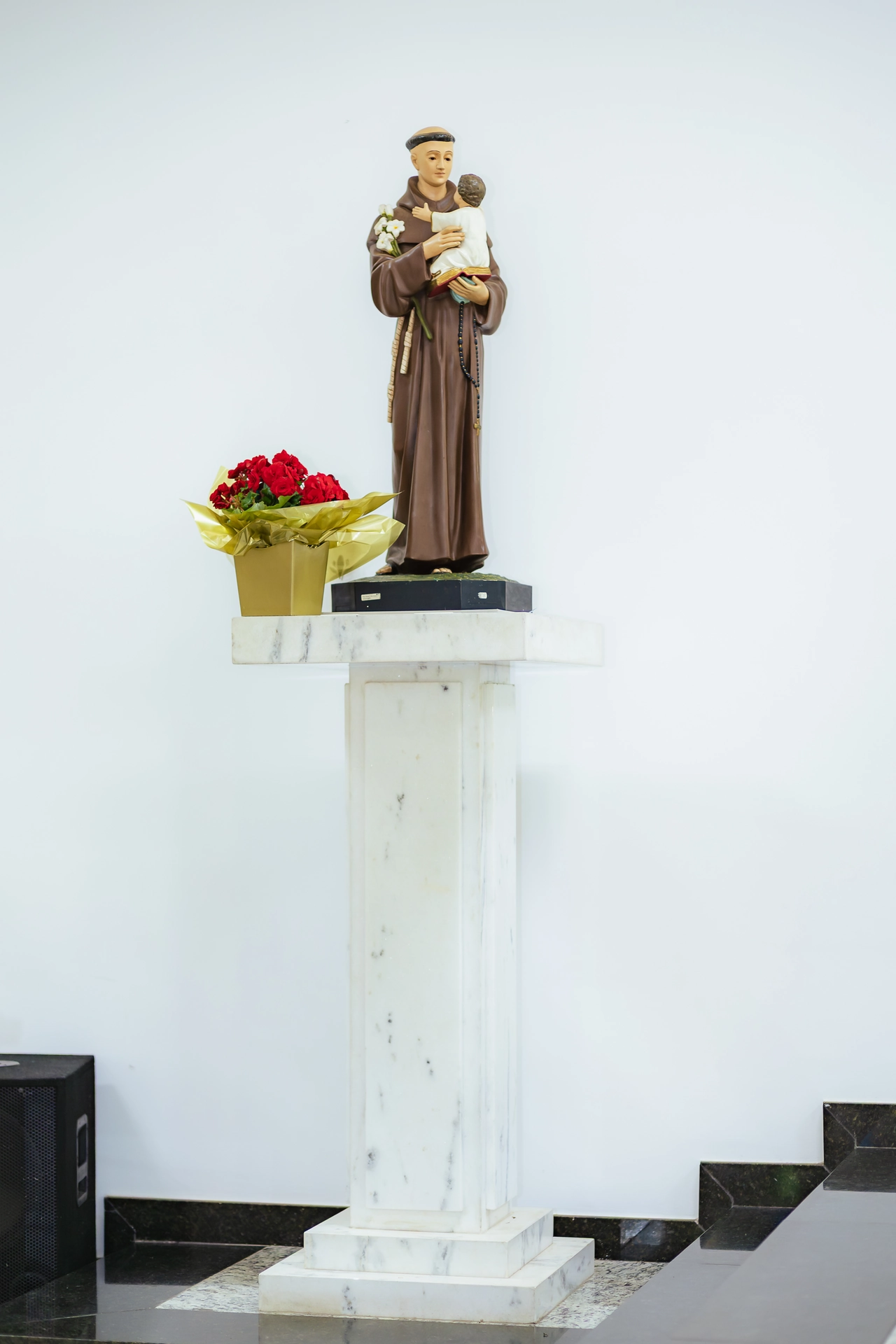 Imagem de santo com um arranjo de flores no altar da igreja