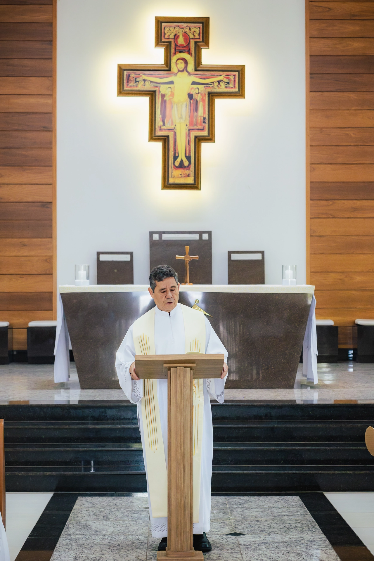 Leitura no ambão durante a cerimônia de batizado, com o crucifixo ao fundo