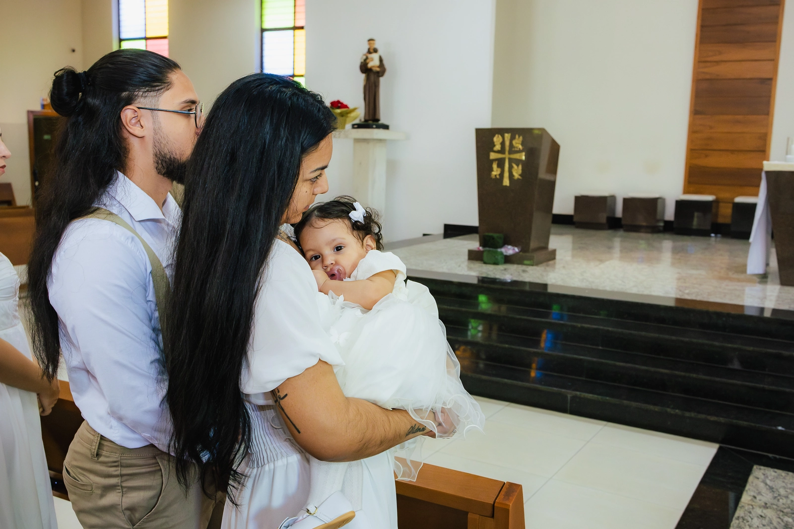 Pais segurando a bebê de pé durante o batizado em Goiânia