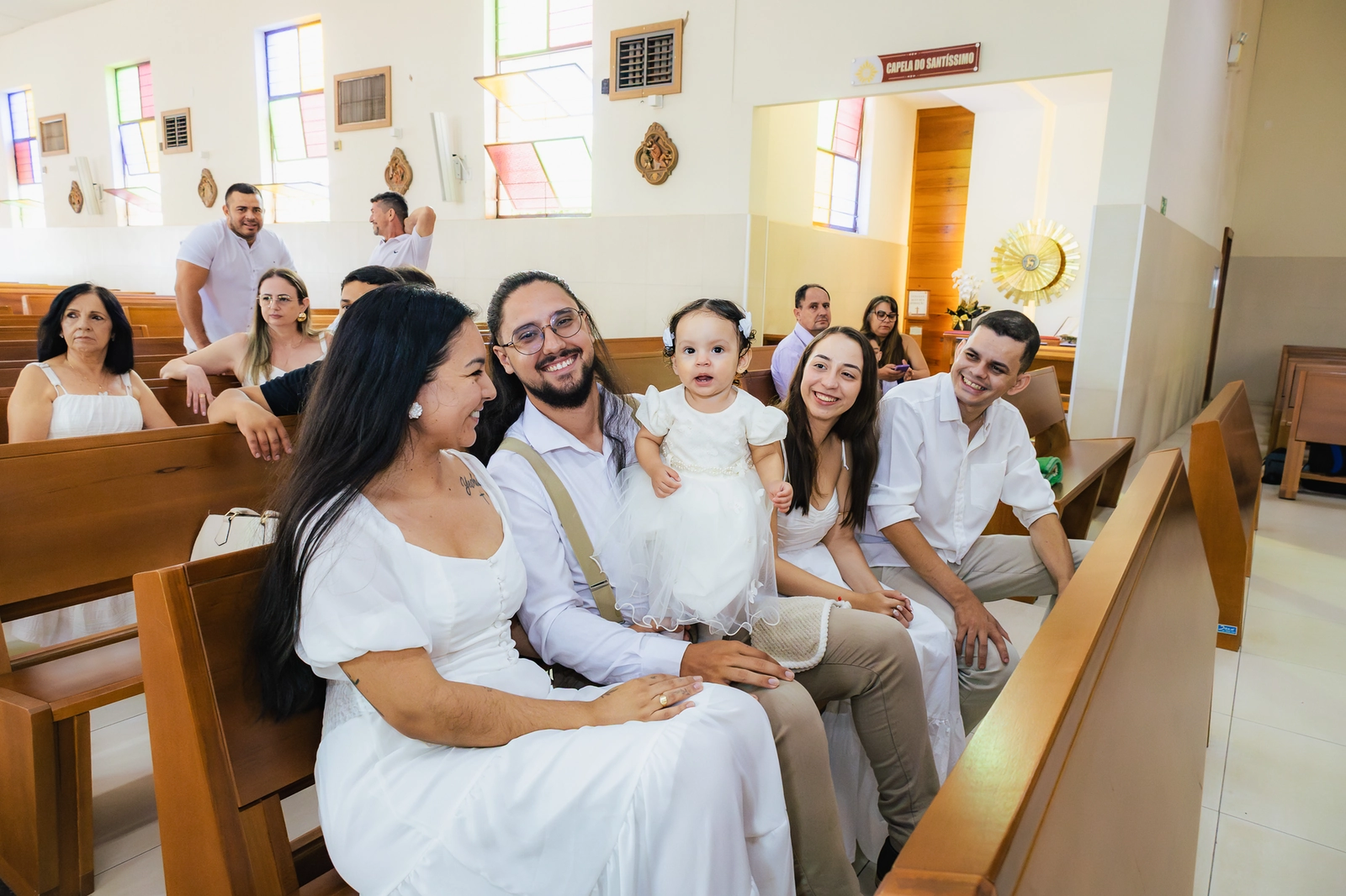 Pais abraçados com a bebê após o batizado