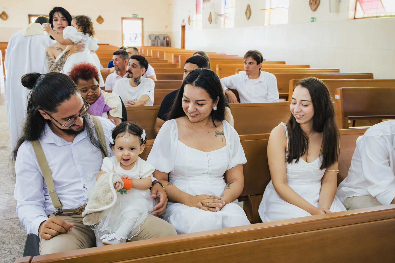 Pais sorrindo com a bebê no banco da igreja