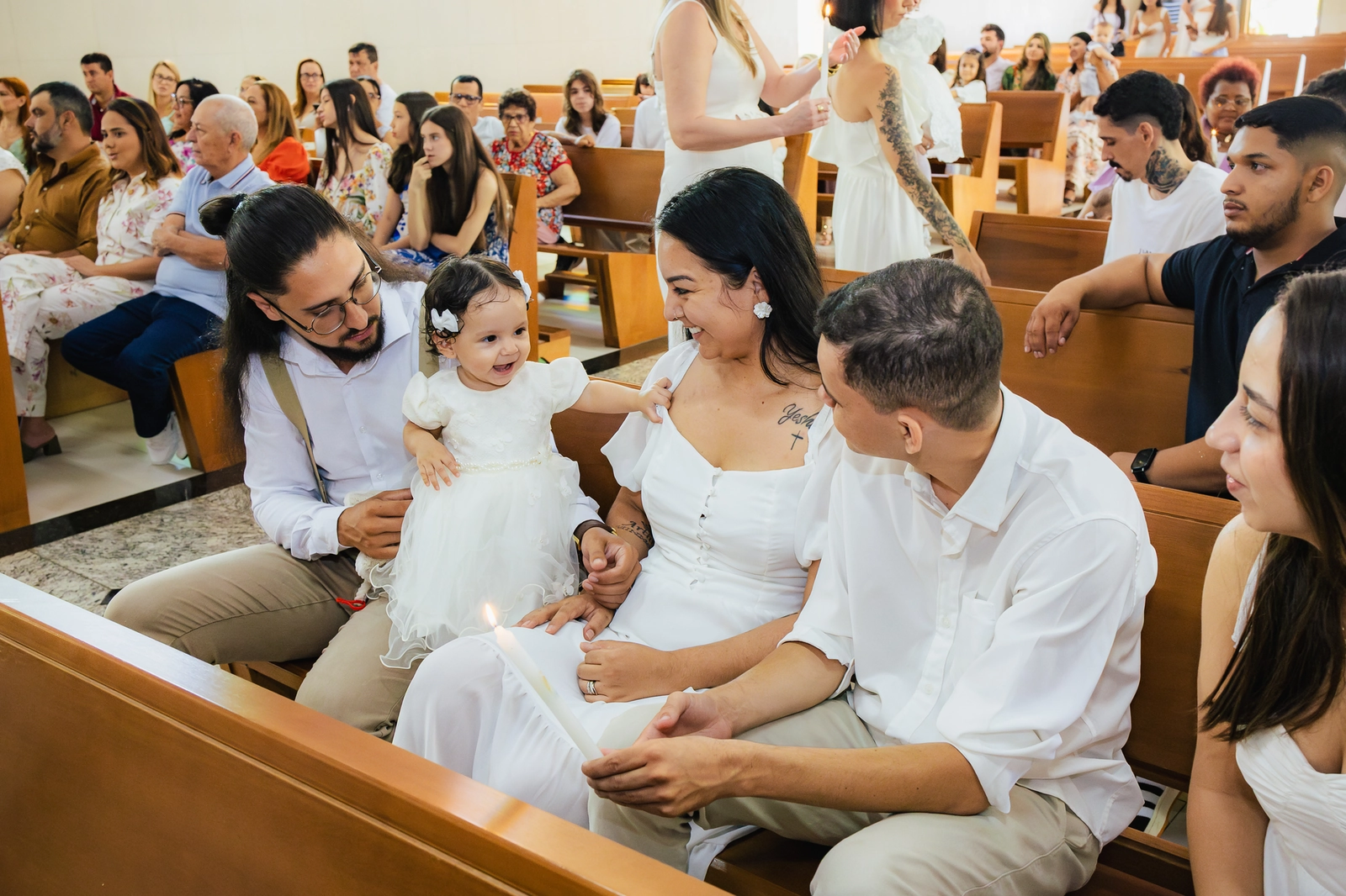 Bebê no colo com familiares durante a celebração do batizado