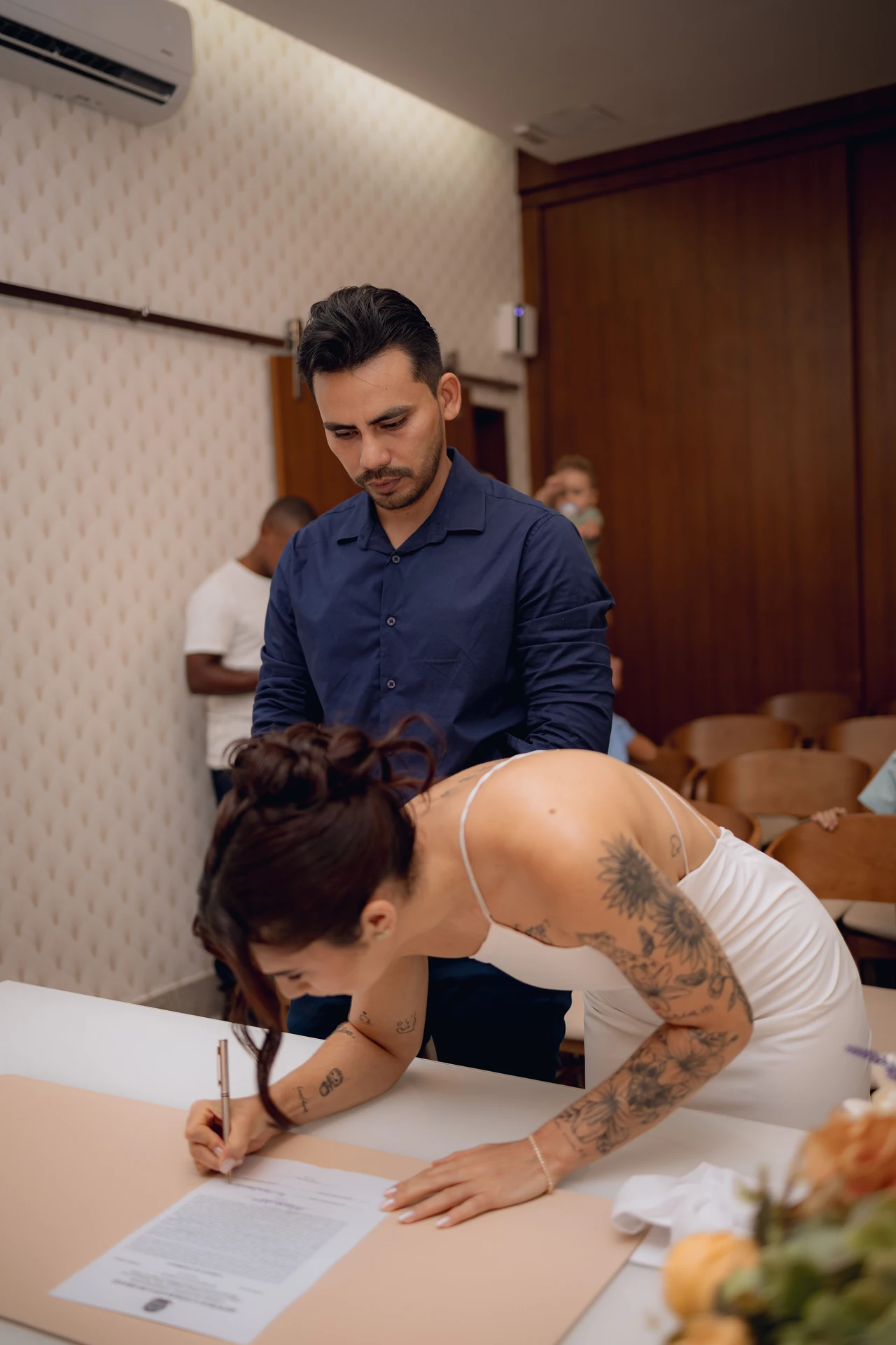 Alice assinando o documento do casamento enquanto José, ao lado, olha o papel