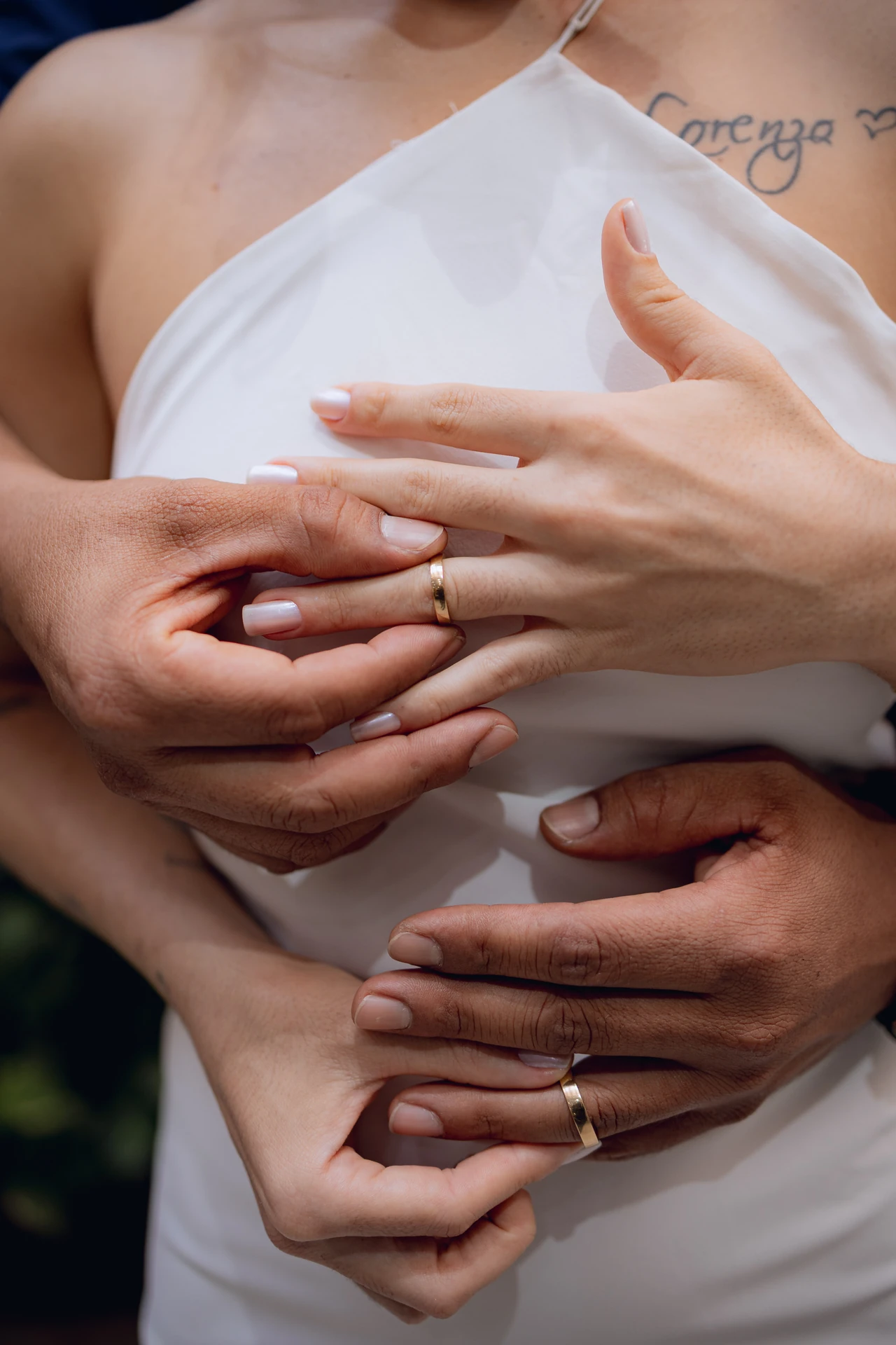 Detalhe das mãos dos noivos sobrepostas, com as alianças douradas à mostra