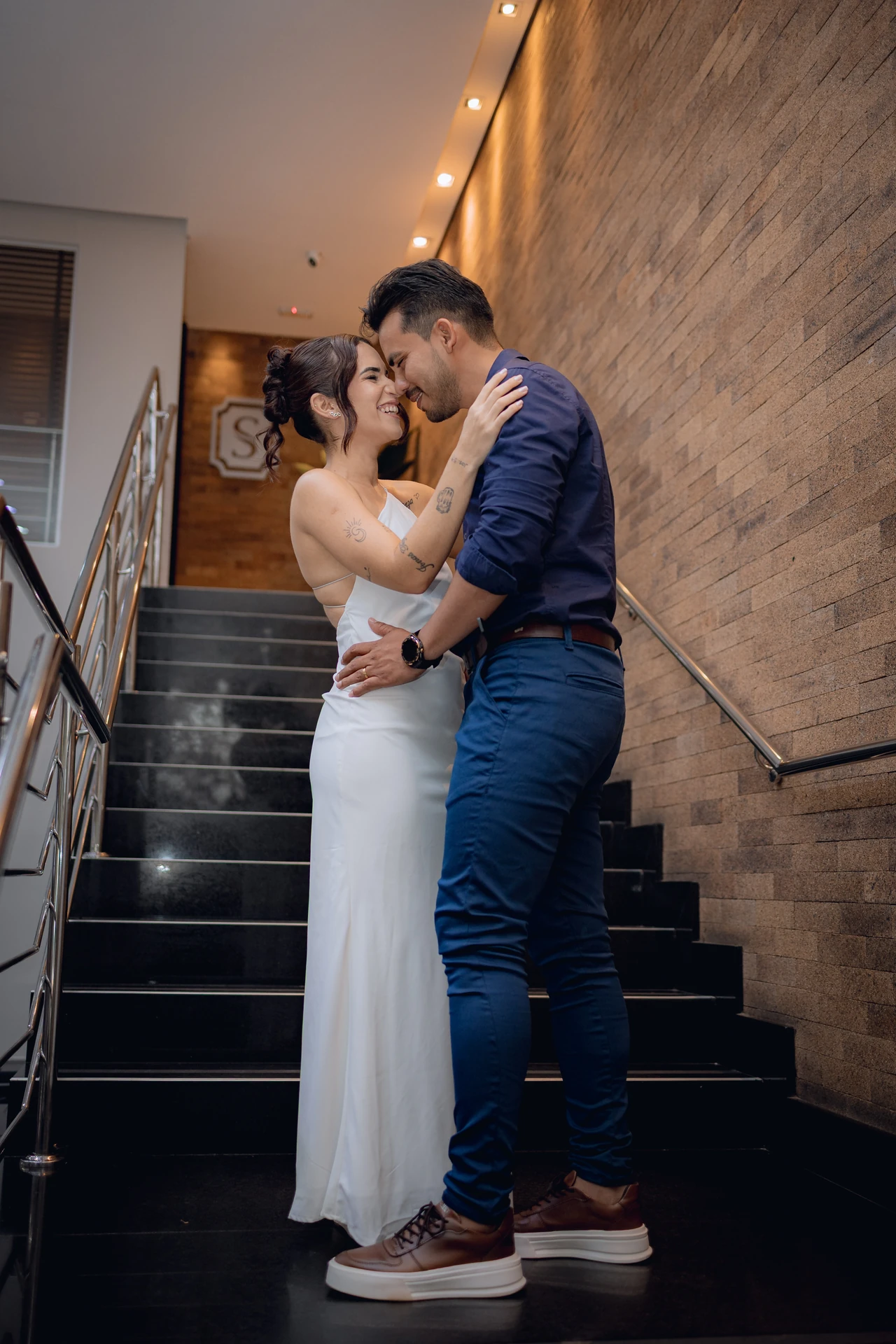 Casal abraçado, quase se beijando, na escada do cartório