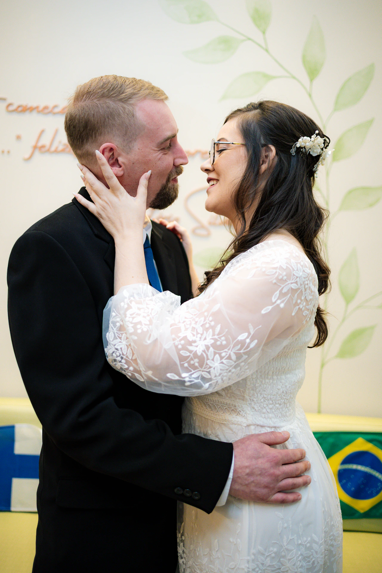 Os noivos quase se beijando, a noiva com as mãos no rosto do noivo