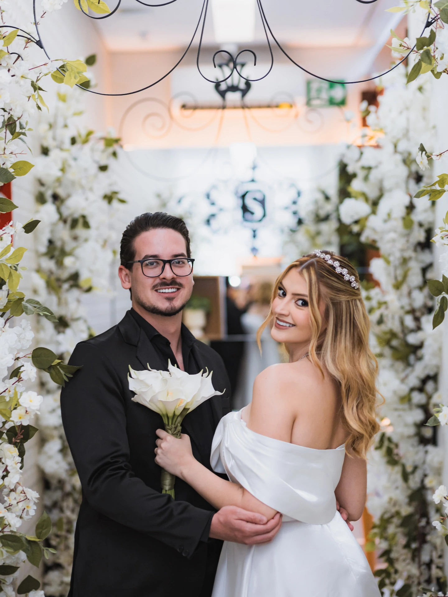 Os noivos abraçados sob o arco florido durante o casamento civil
