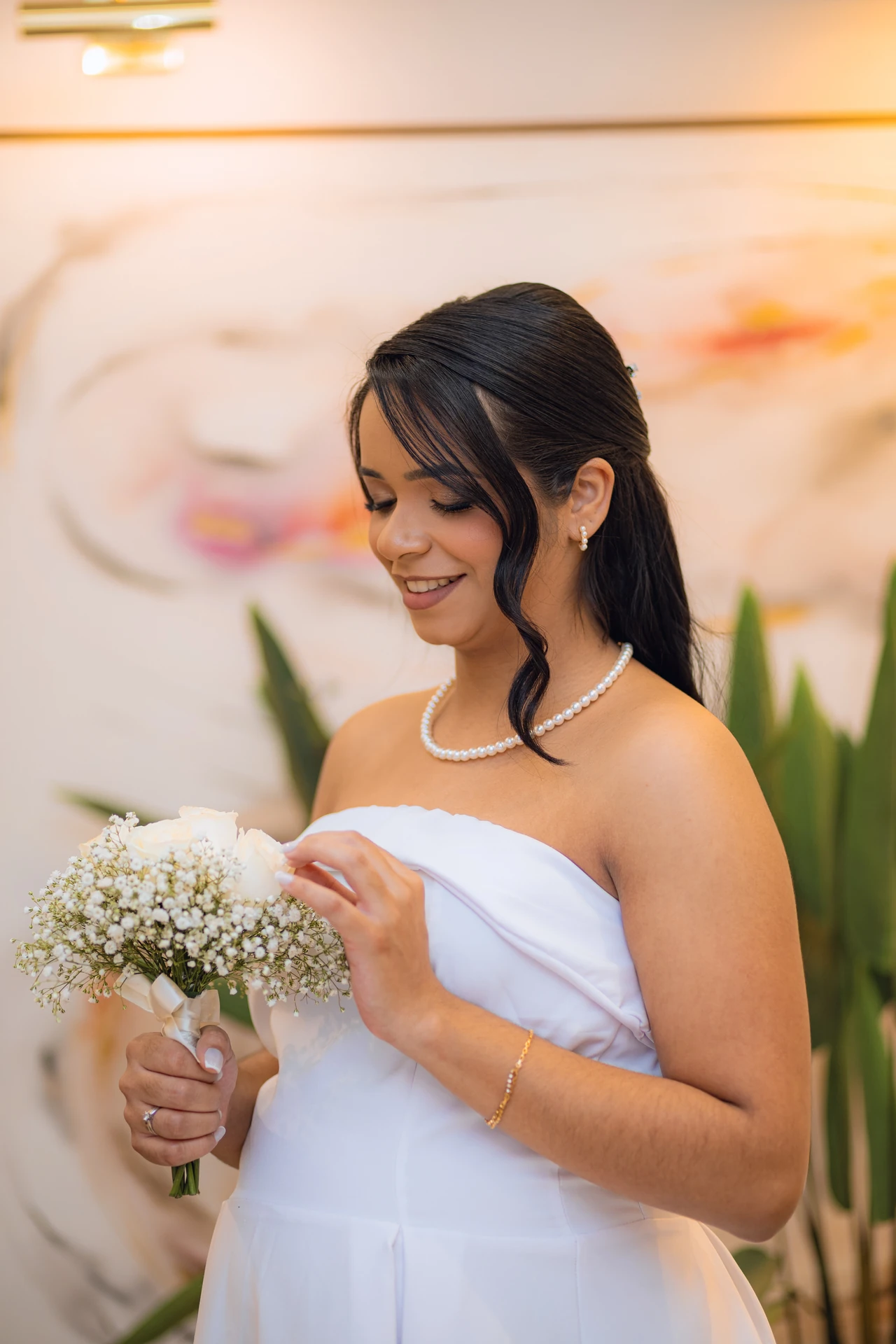 Jéssica sorrindo e ajustando o vestido, com o buquê de rosas brancas nas mãos