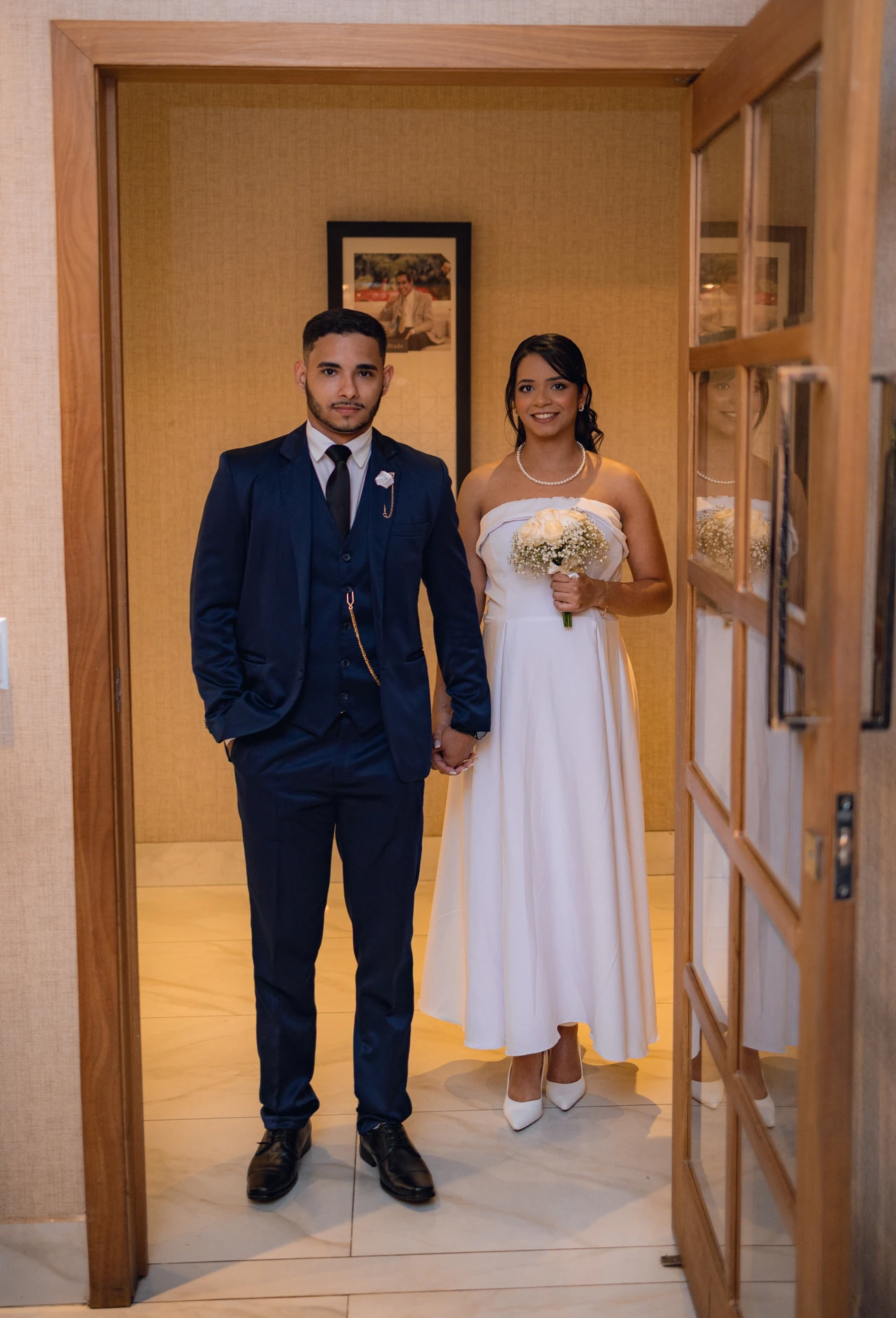 Jéssica e Thiago em pé na entrada da sala do cartório, prontos para a cerimônia