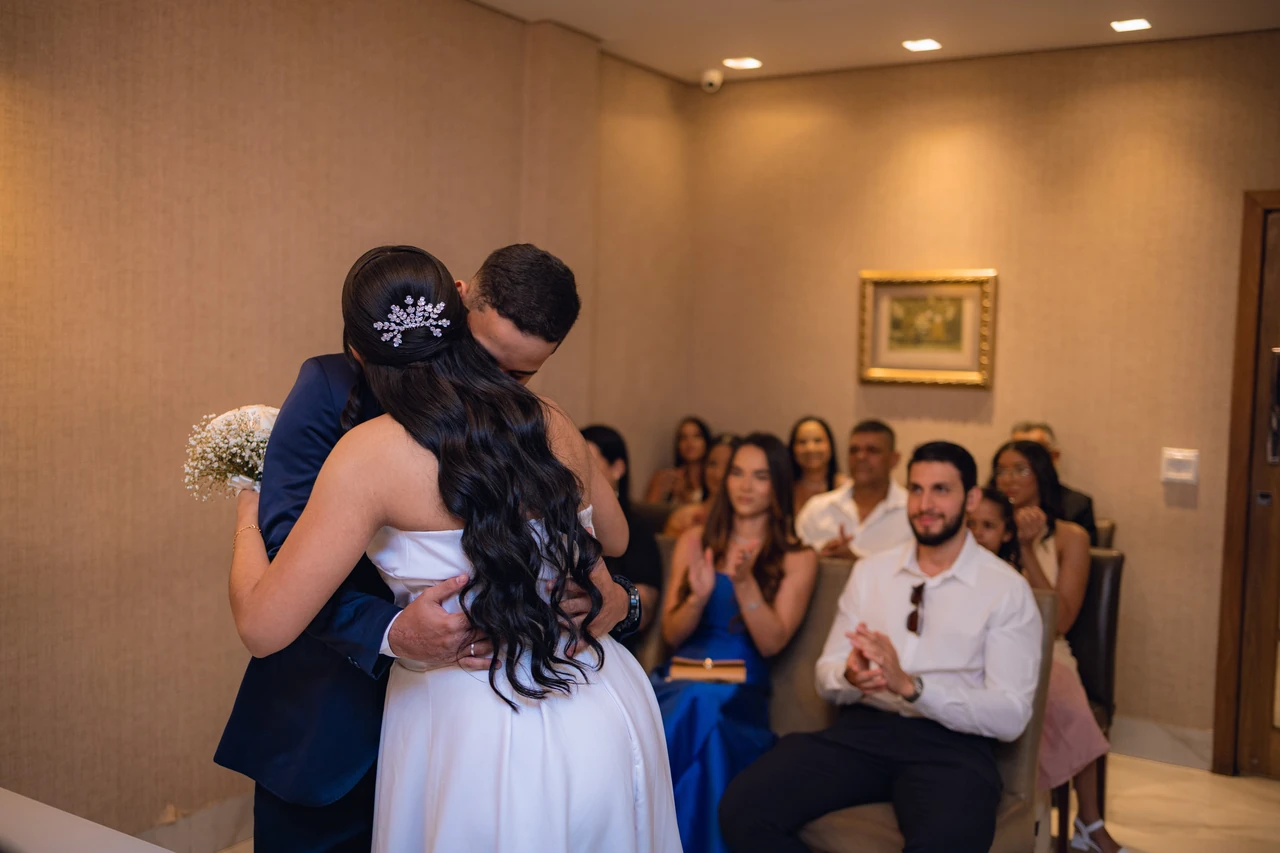 Jéssica e Thiago se abraçando emocionados logo após o sim, com os convidados aplaudindo ao fundo