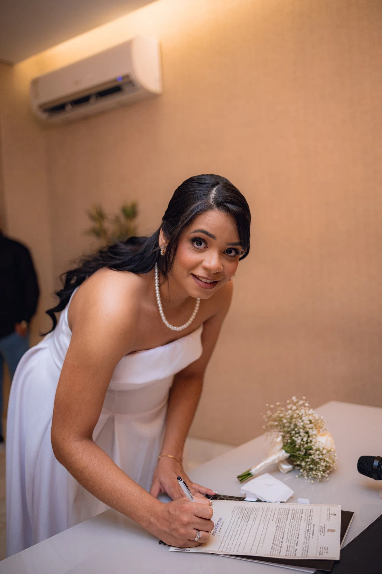 Jéssica assinando o livro de registro do casamento civil, sorrindo para a câmera
