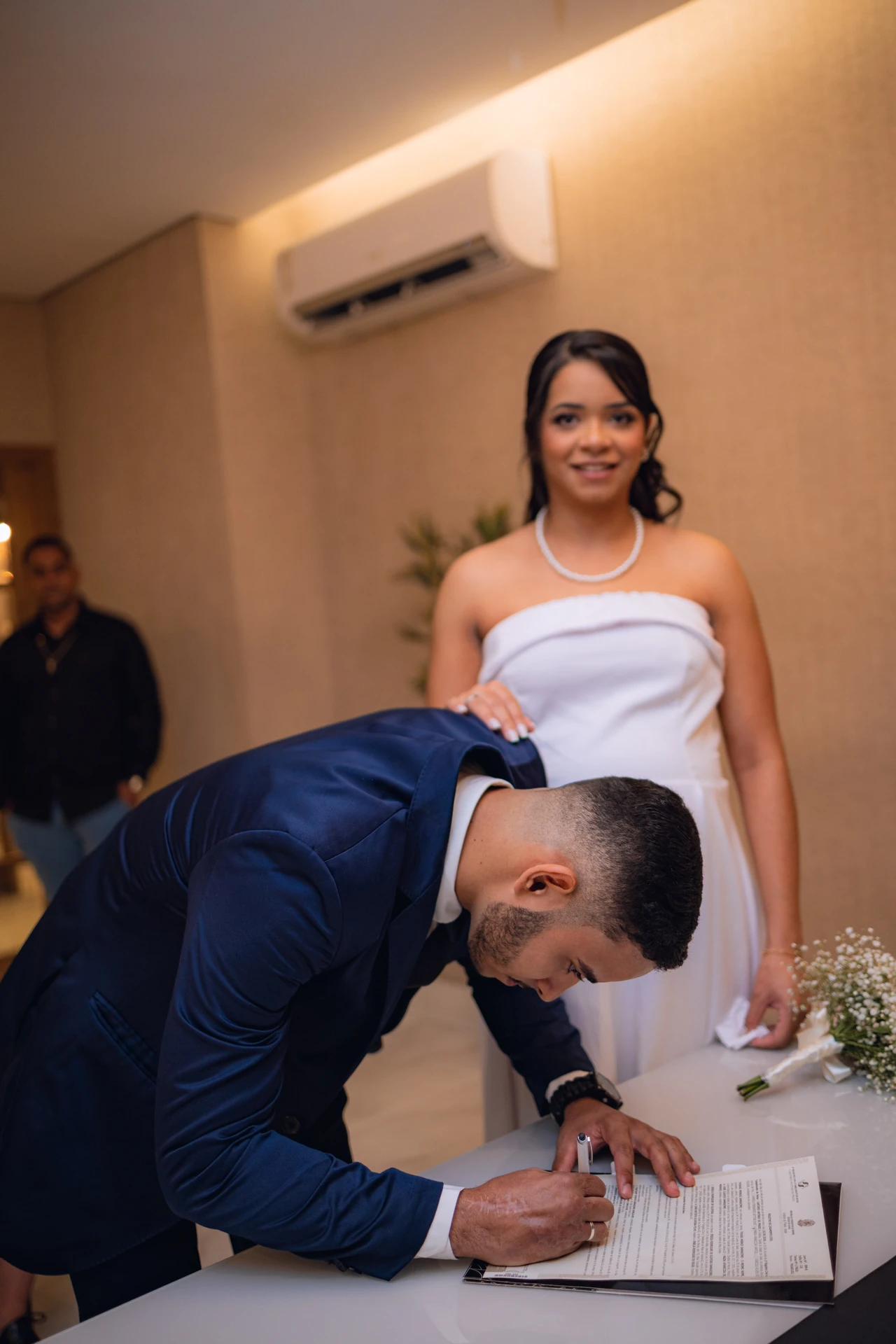 Thiago assinando o livro de registro do casamento civil, com Jéssica ao lado
