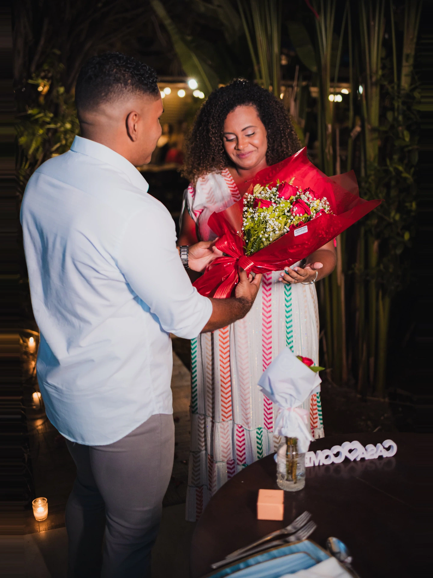 Homem entregando um buquê de rosas vermelhas à namorada emocionada