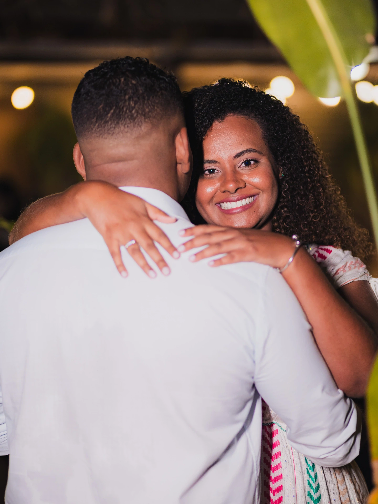 Mulher abraçando o namorado e sorrindo para a câmera durante o ensaio de noivado