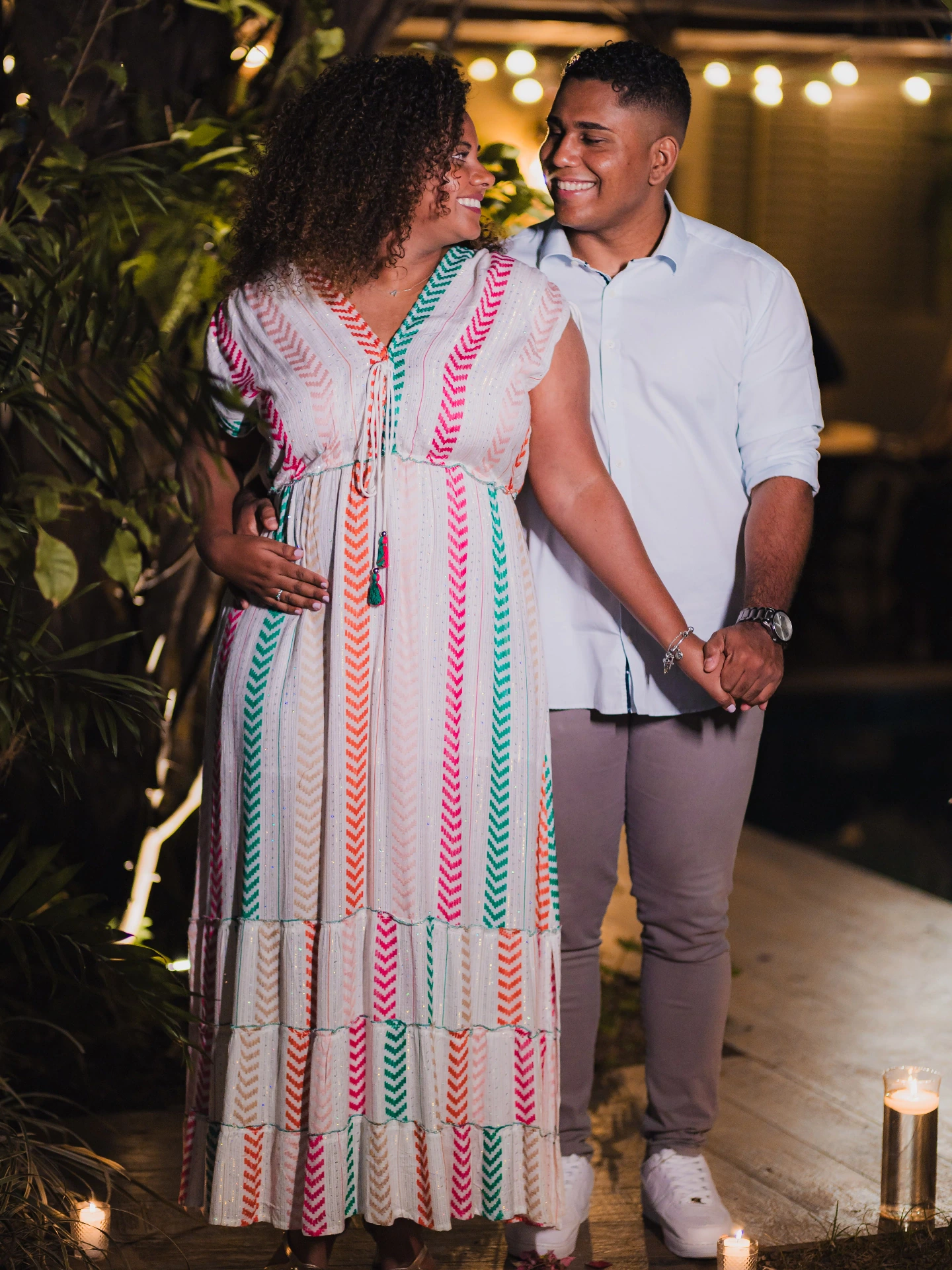 Casal se beijando de mãos dadas, com uma vela acesa ao lado