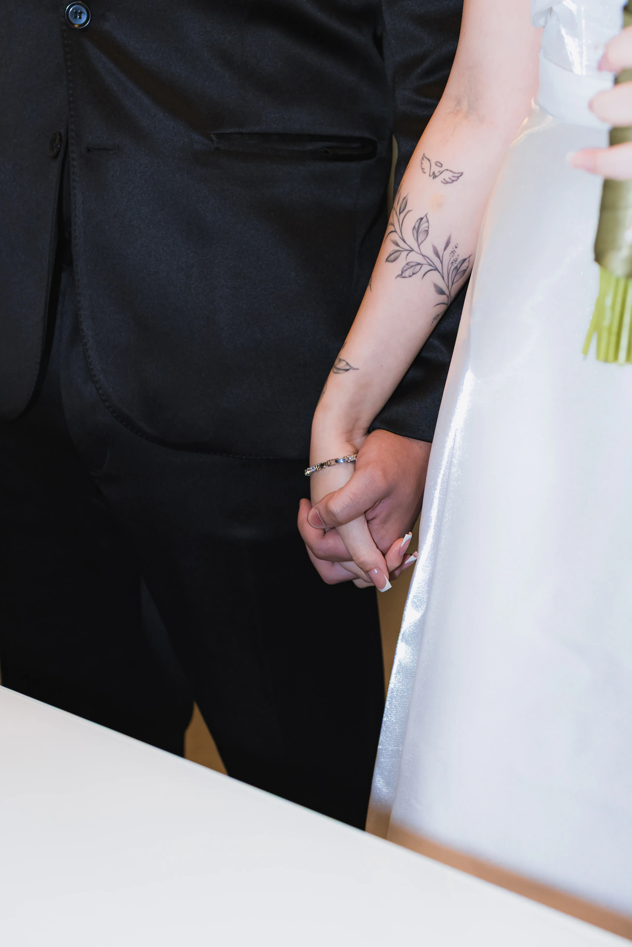 Noivos de mãos dadas durante a cerimônia de casamento civil, o noivo segurando o buquê da noiva