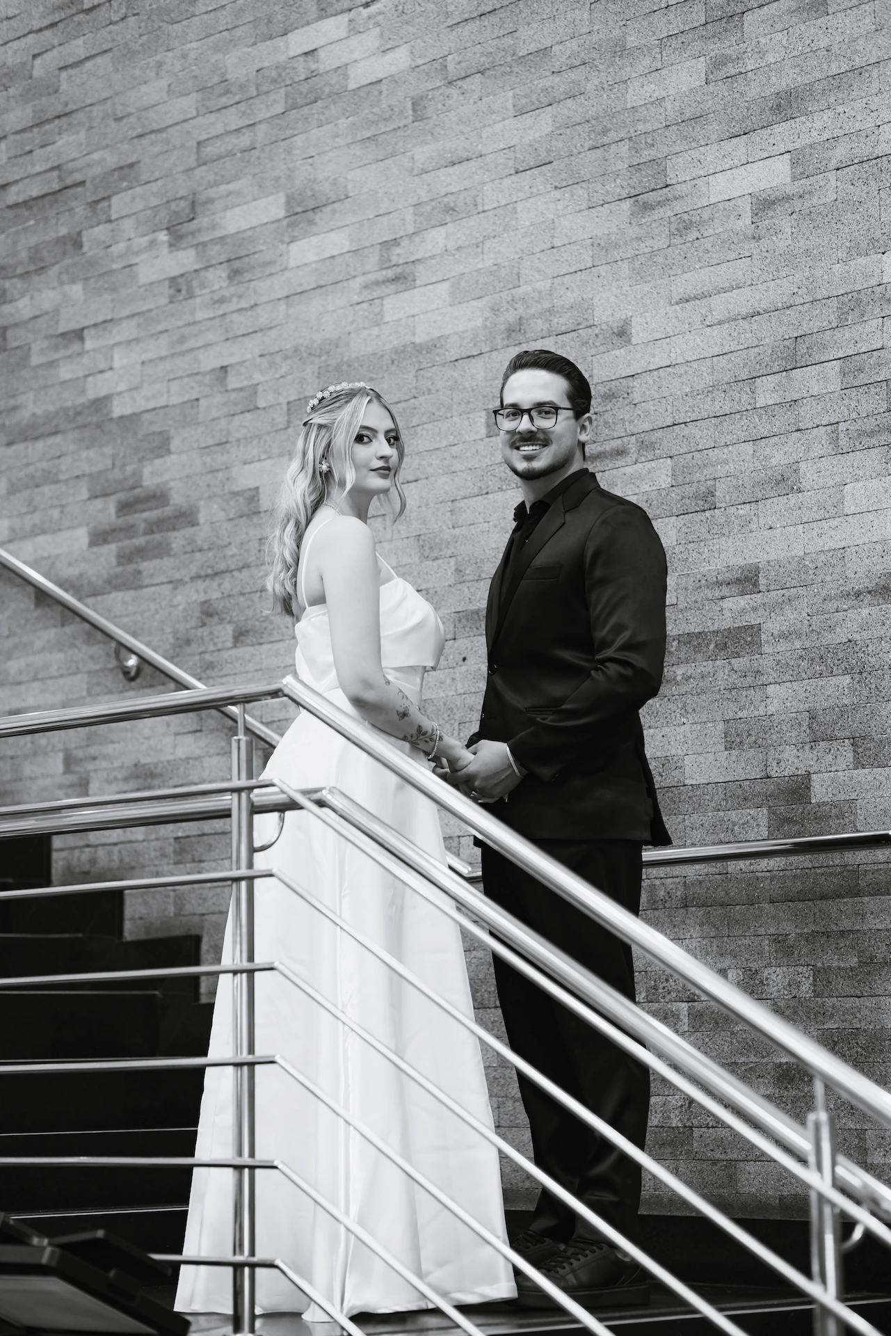 Retrato em preto e branco dos noivos na escada do cartório após o casamento civil