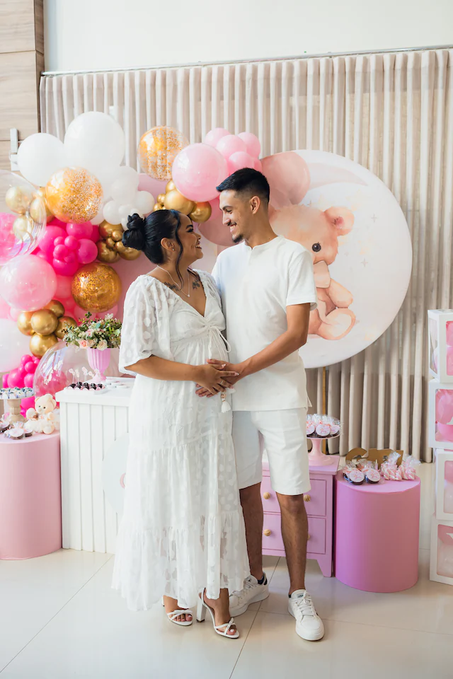 Casal grávido sorrindo em festa de chá de bebê em Goiânia