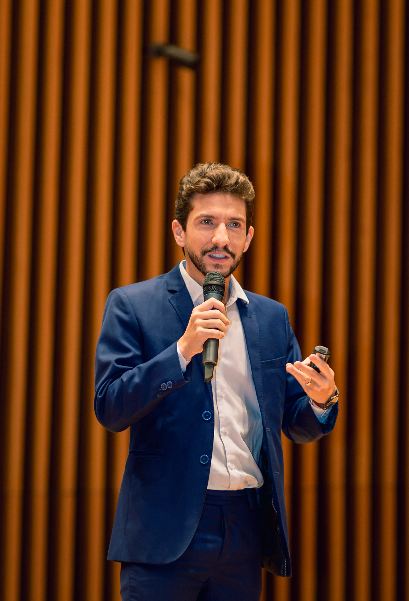 Palestrante de terno azul falando ao microfone durante evento empresarial em Goiânia
