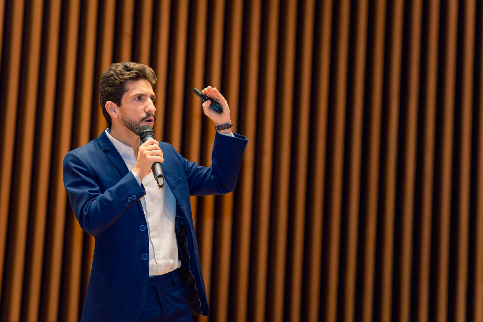 Palestrante gesticulando ao microfone durante o evento empresarial