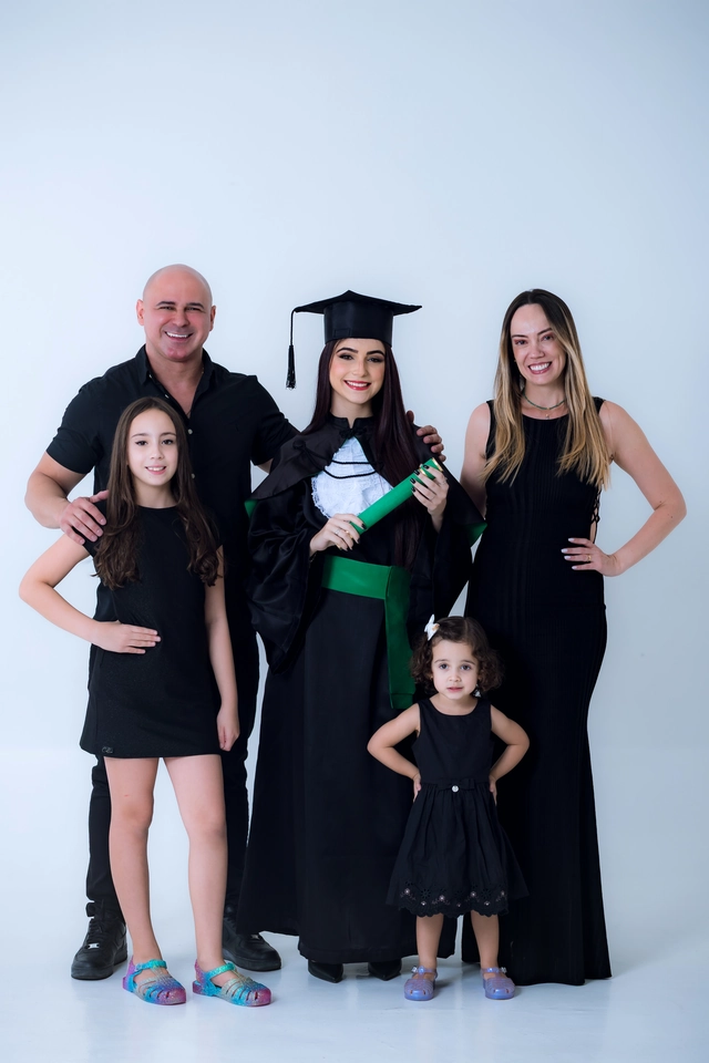 Família reunida para o ensaio de formatura em estúdio, com pai, mãe e irmãs