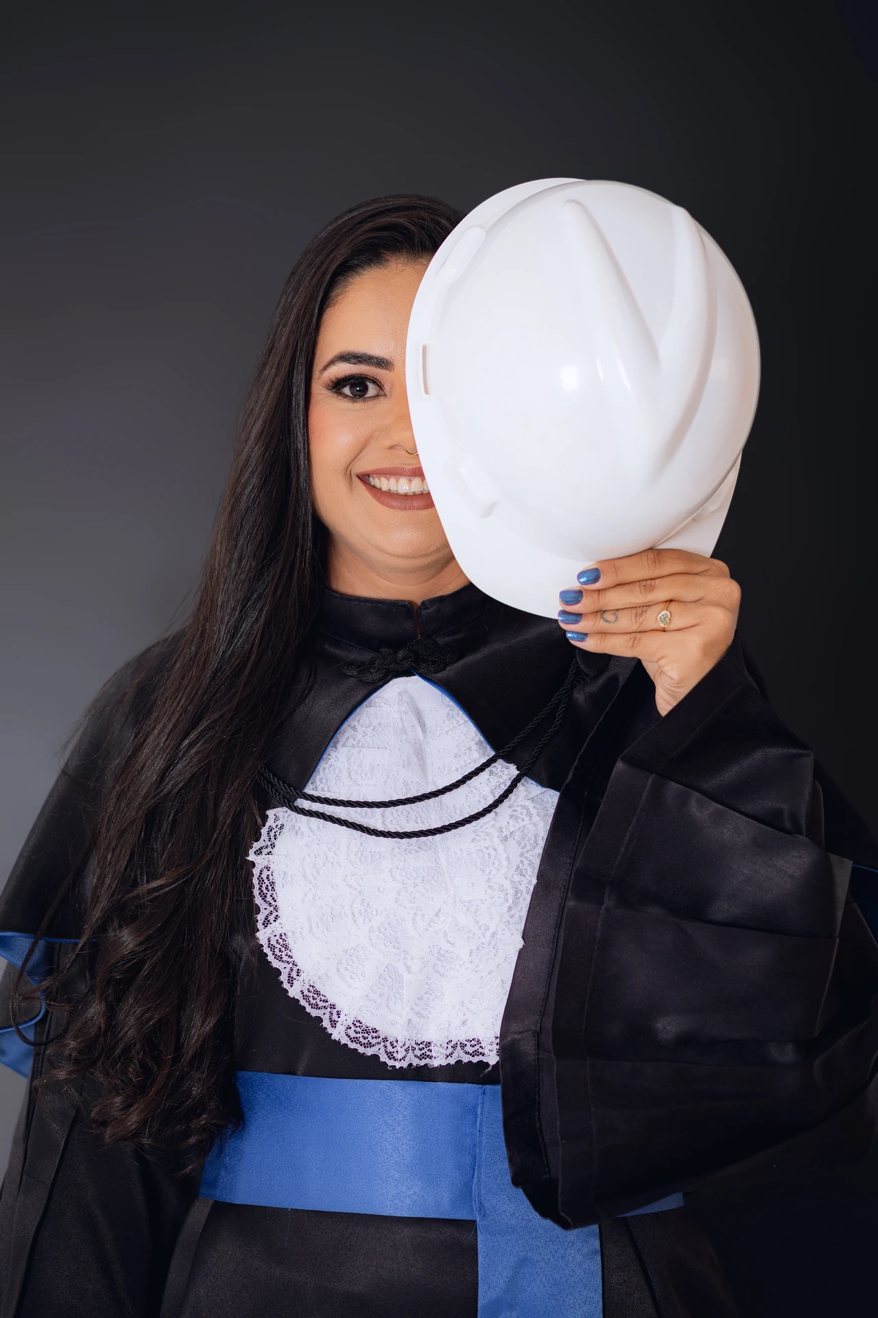 Formanda sorrindo com o capacete de engenharia cobrindo parte do rosto