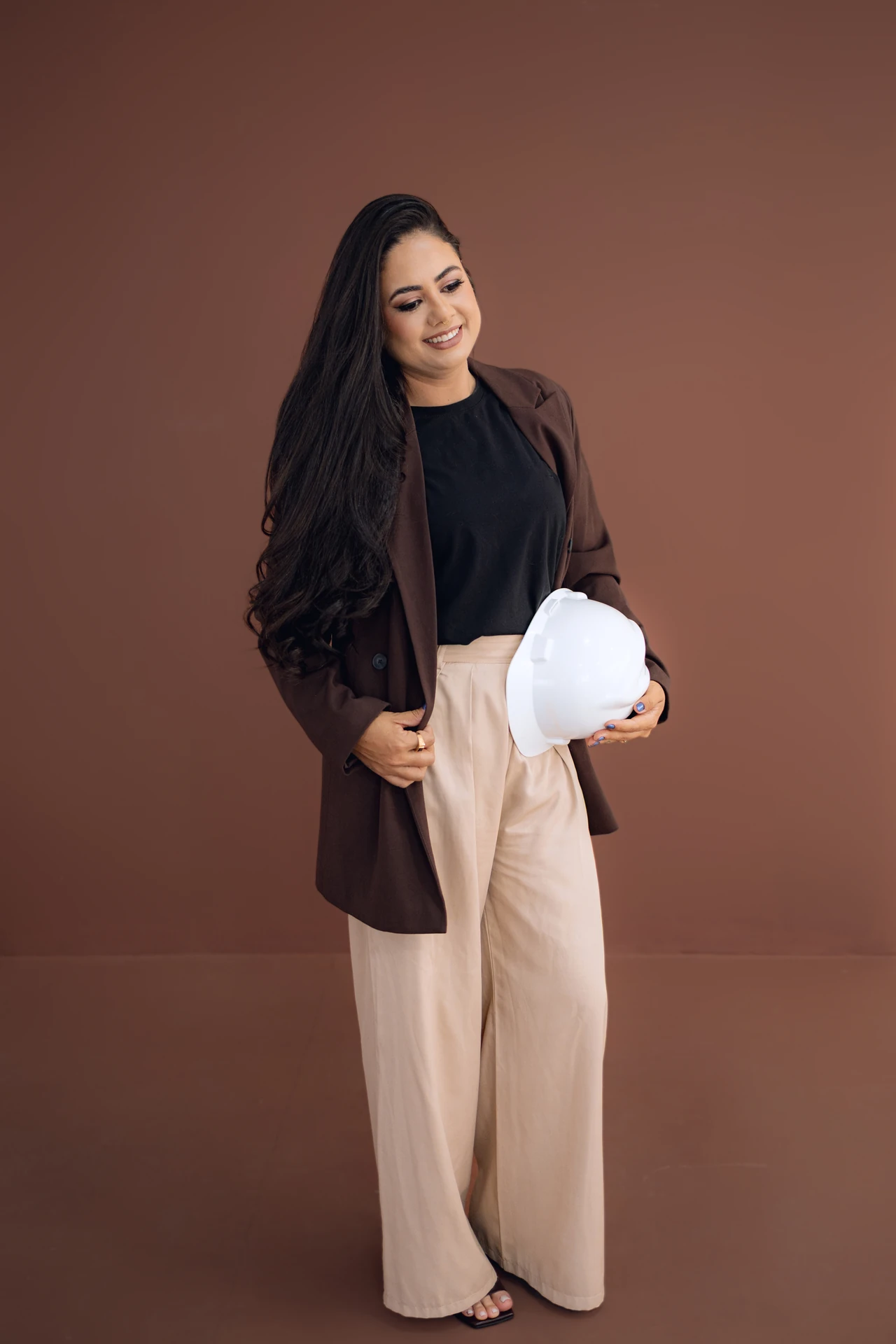 Formanda de corpo inteiro, look profissional de engenharia, fundo marrom