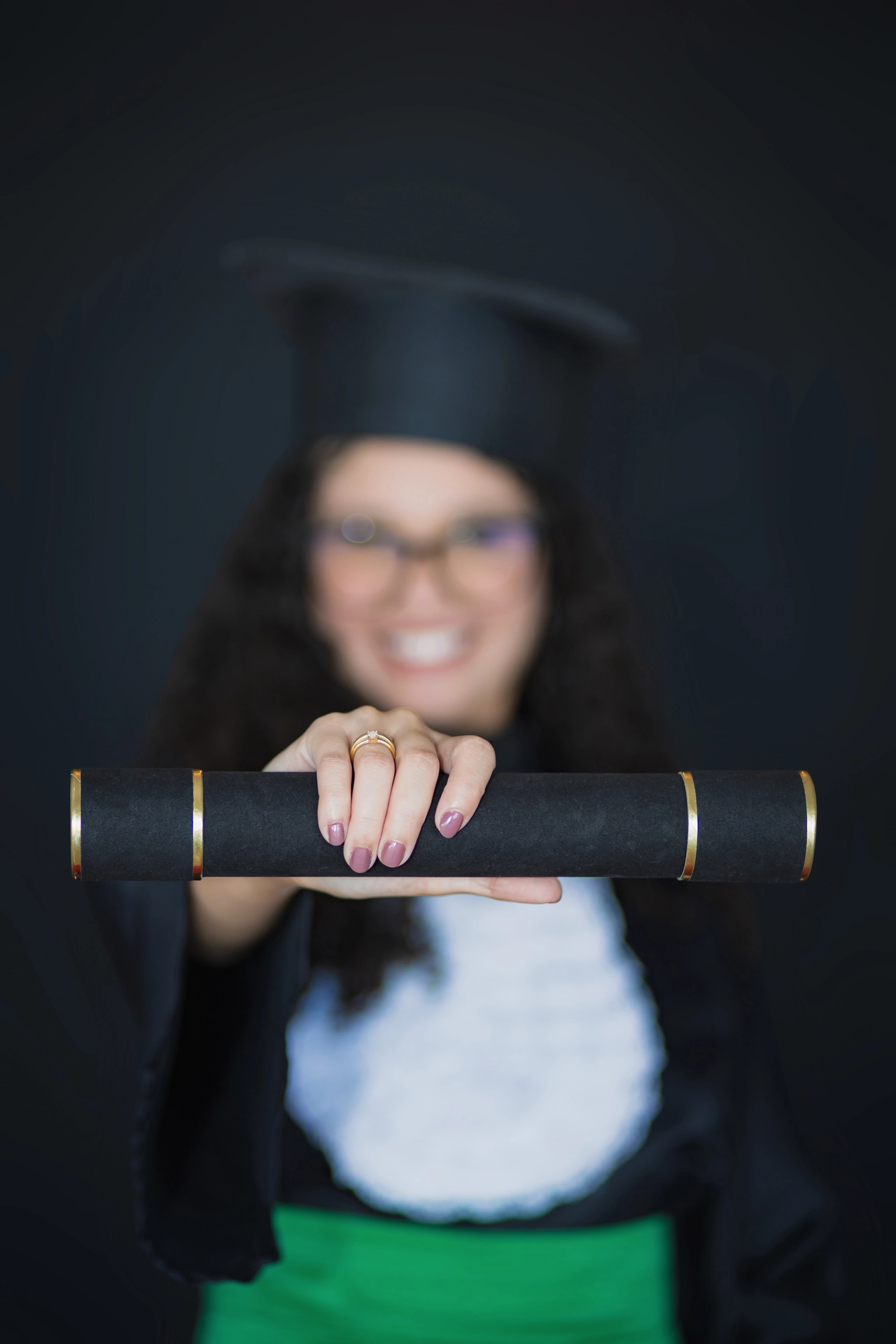 Diploma em primeiro plano, com a formanda desfocada ao fundo