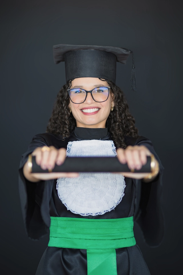 Formanda segurando o diploma com as duas mãos, retrato de formatura em estúdio