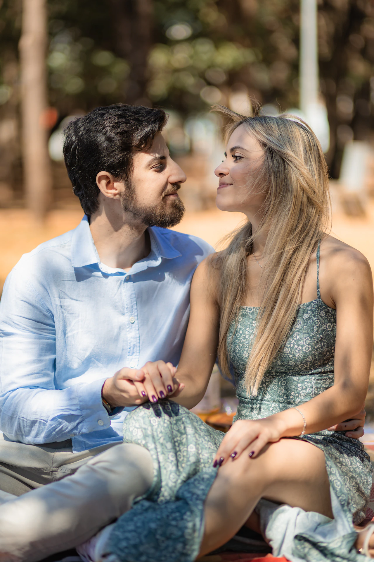 Casal sentado no gramado do parque durante o ensaio de noivado
