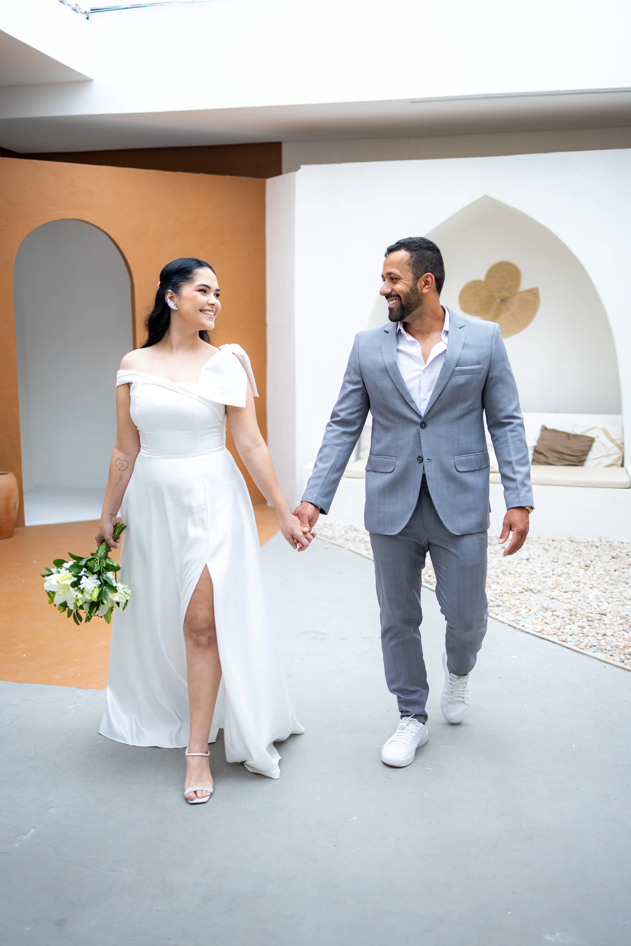 Casal de mãos dadas caminhando durante o ensaio pré-wedding em Goiânia, a noiva com buquê
